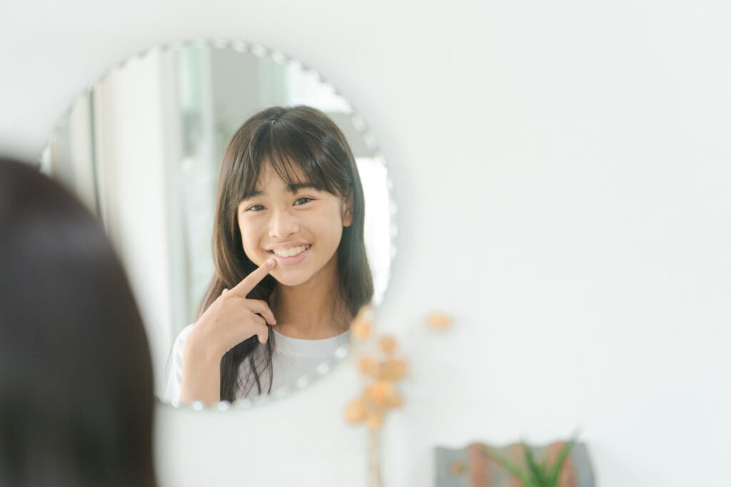 鏡で口元を見る小学生女子